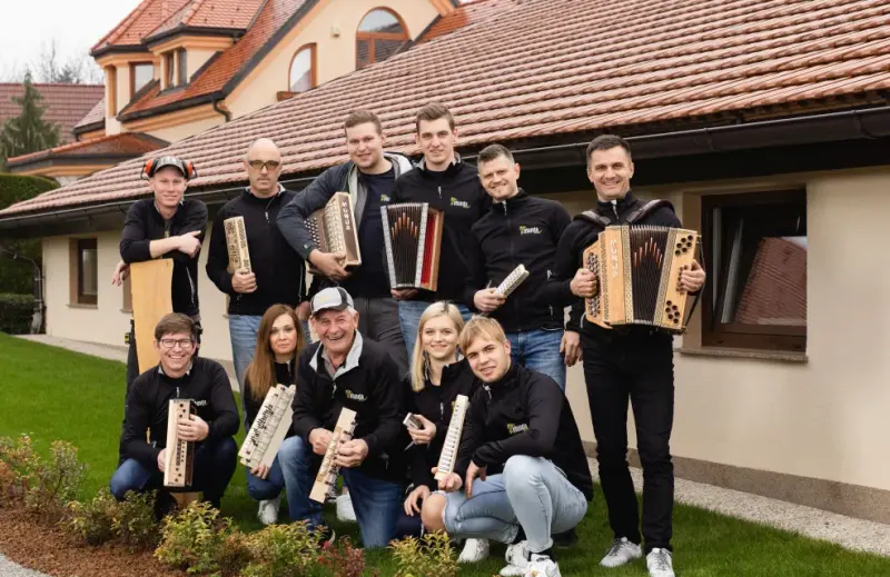 Kolektiv delavnice Munda s harmonikami pred hišo